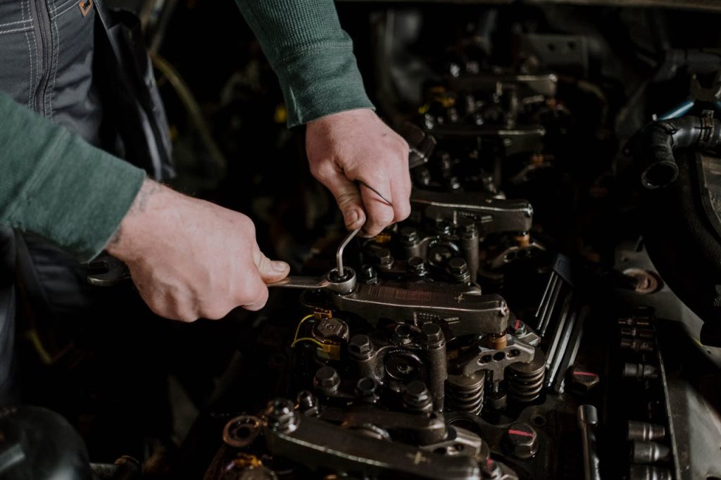 a-person-fixing-a-machine-7564871 Close-up of a mechanic using hand tools to fix an engine, showcasing precision and skill.